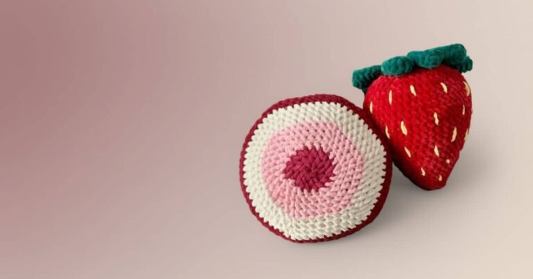 Close-up de capa de almofada de crochê em forma de morango e outra redonda com listras rosa, branca e vinho.