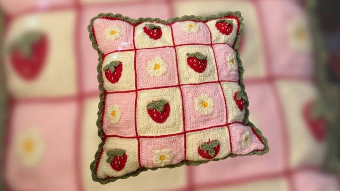 Capa de almofada de crochê com estampa de morangos e flores, ideal para decoração.