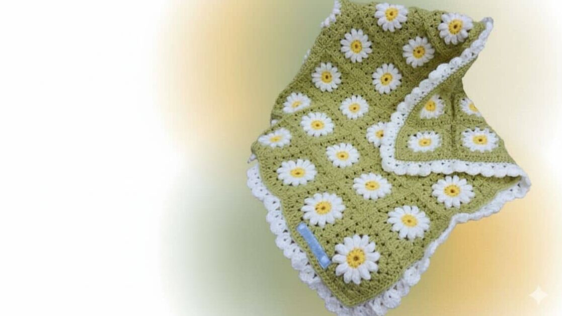 Manta de crochê granny square verde com margaridas brancas e amarelas, borda rendada branca.