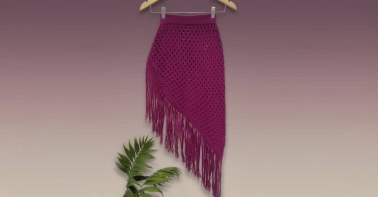 Saia de crochê magenta com franjas pendurada em um cabide contra um fundo gradiente roxo e bege.