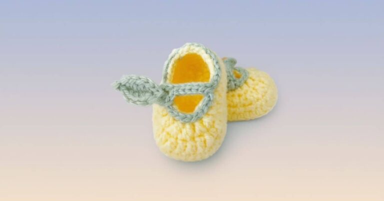 Um par de sapatinhos de limão siciliano em crochê, com detalhes em verde claro, lado a lado sobre um fundo suavemente gradiente.