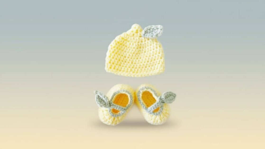 Conjunto de crochê para bebê: sapatinhos e touca amarela com detalhes em formato de folhas.