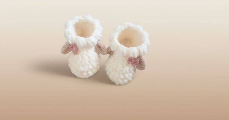 Dois sapatinhos de crochê brancos com design de ovelha e laço rosa.
