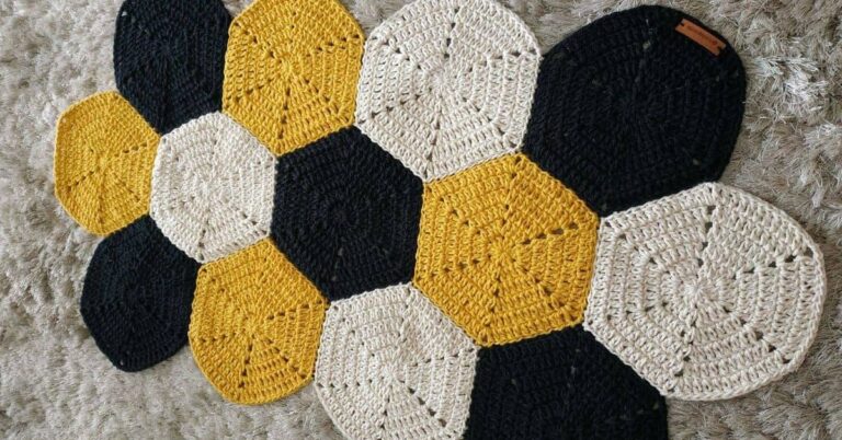 Tapete de crochê com hexágonos coloridos em preto, amarelo e bege.