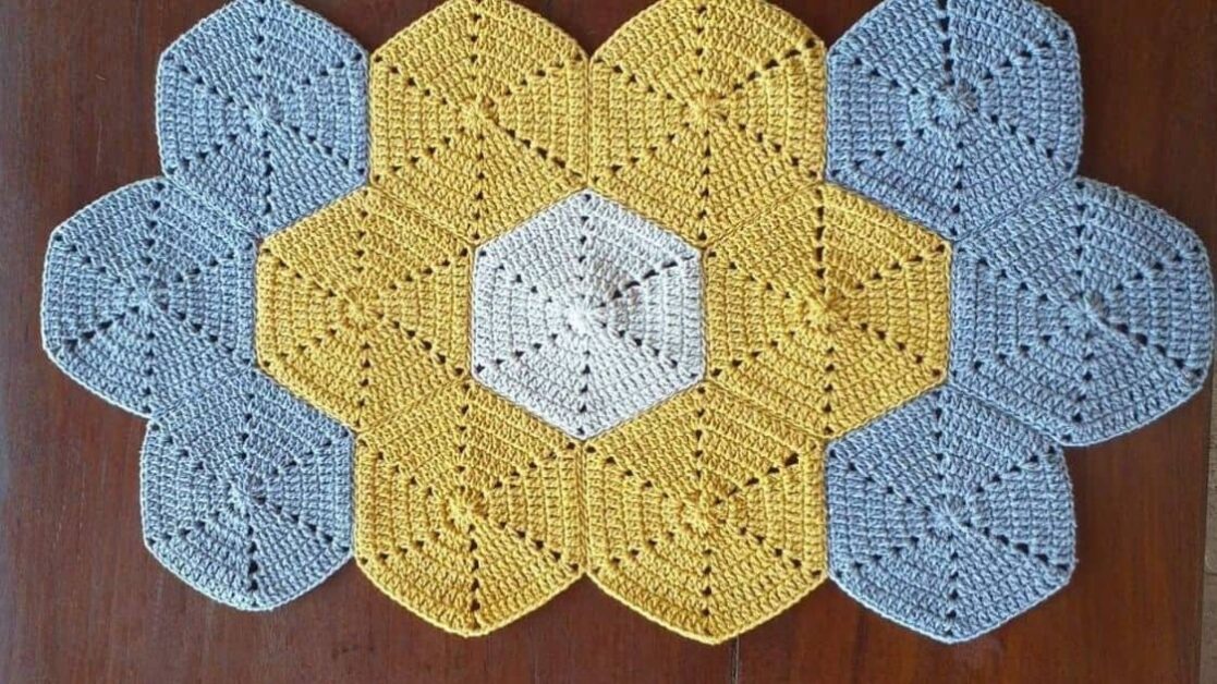Tapete de crochê com hexágonos em tons de cinza, amarelo e branco.
