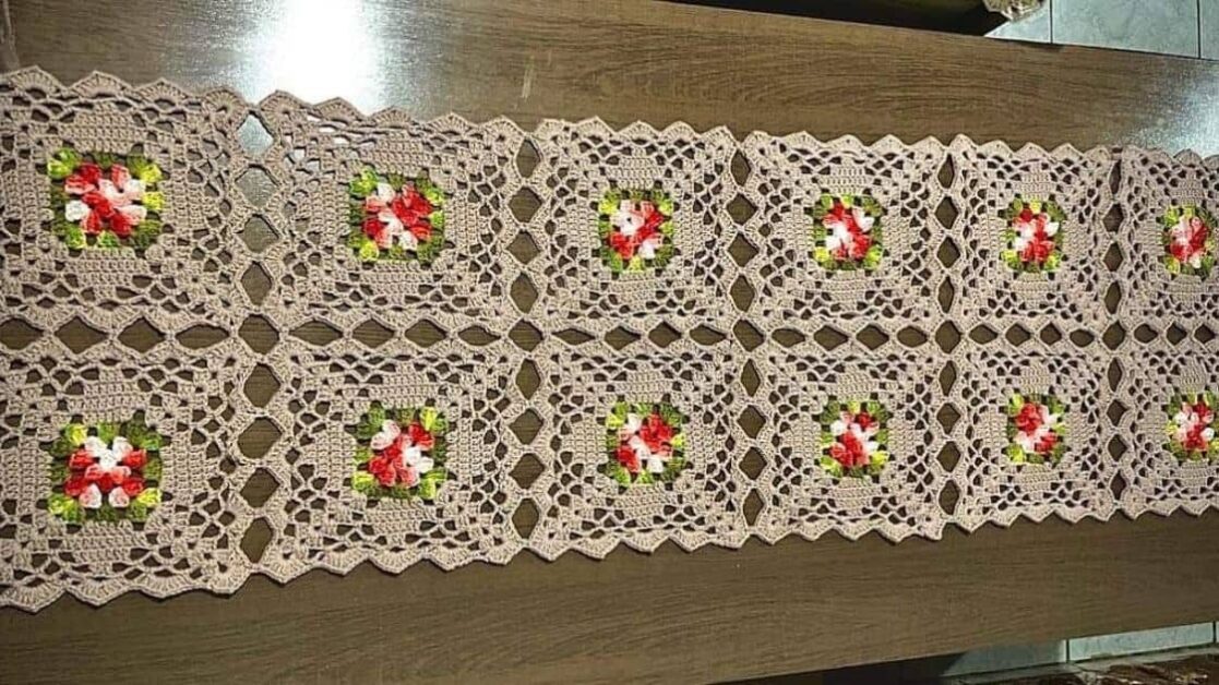 Trilho de mesa geométrico quadrado de crochê com flores vermelhas e brancas.